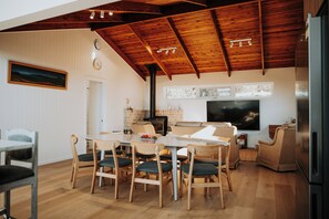 Un vaste espace de vie doté d’un haut plafond, d’une cheminée, d’une table à manger avec des chaises et d’un téléviseur.