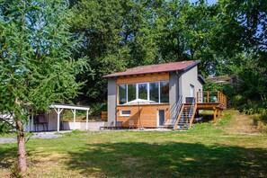 Ein modernes, zweistöckiges Haus mit Holzterrasse und überdachter Veranda.