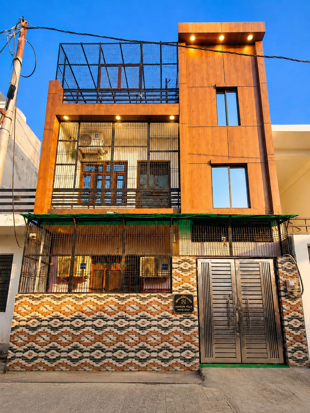 Un edificio moderno de dos pisos con un balcón, ventanas amplias y una pared con diseño.