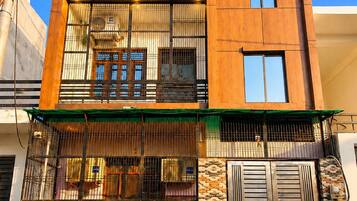 Un edificio moderno de dos pisos con un balcón, ventanas amplias y una pared con diseño.