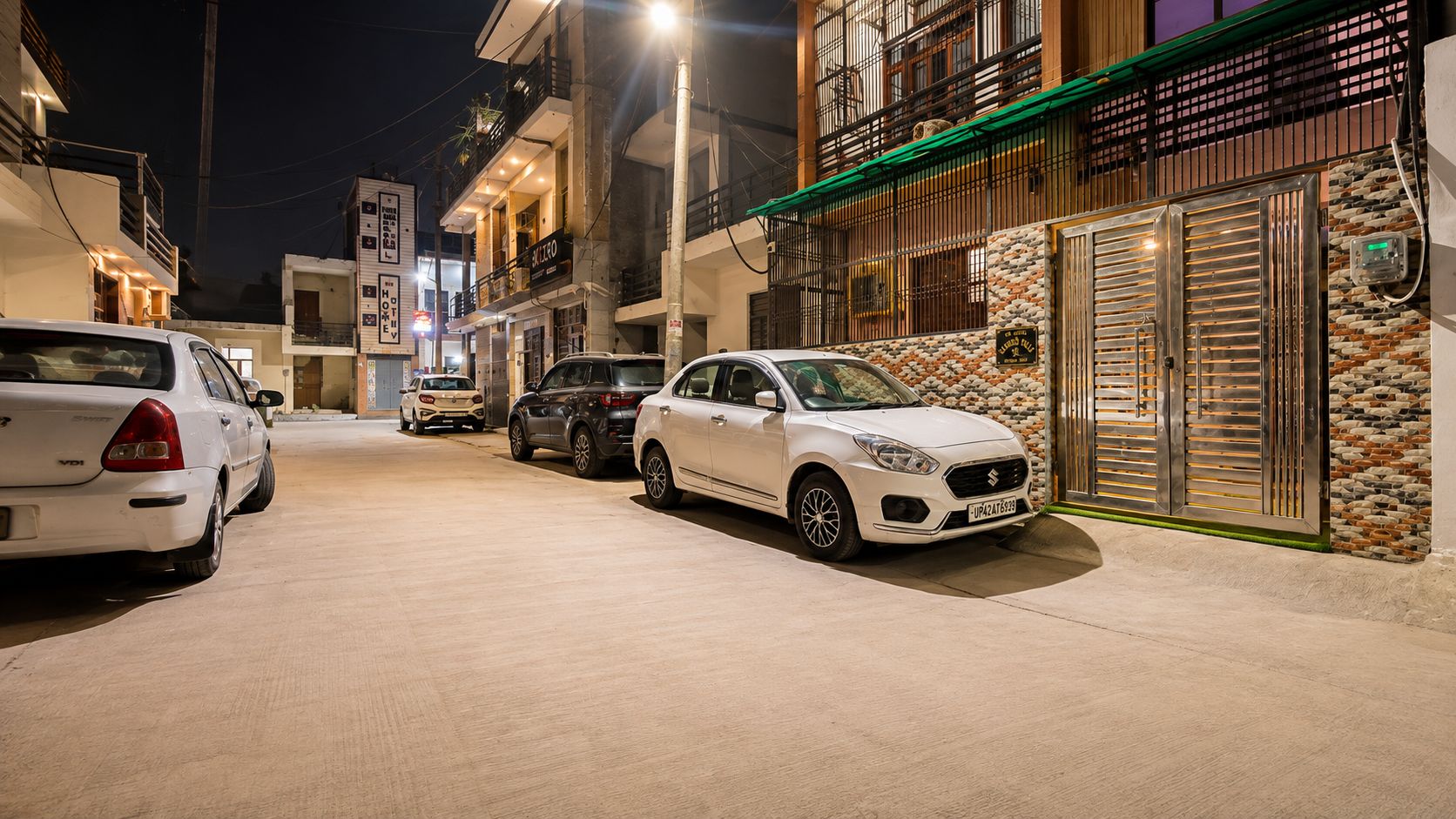 A street at night with parked cars and buildings.