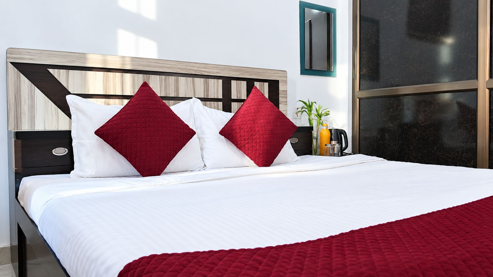 A hotel room with a bed, a nightstand, a coffee maker, and a window.