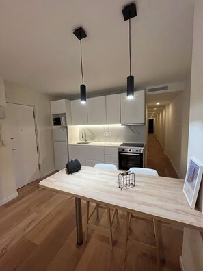 A modern kitchen with white cabinets, a wooden dining table, and black pendant lights. - Large House in Downtown Alicante (Alacant)