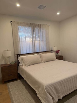 A bedroom with a bed, nightstands, a lamp, and a window with curtains. - New Ultra Luxury Retreat minutes from Arcadia! (Phoenix)