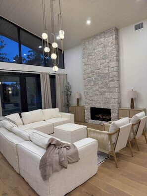 A modern living room with a sectional sofa, a stone fireplace, and pendant lighting. - New Ultra Luxury Retreat minutes from Arcadia! (Phoenix)