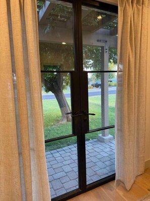 A glass door with a view of a paved outdoor area and a tree. - New Ultra Luxury Retreat minutes from Arcadia! (Phoenix)