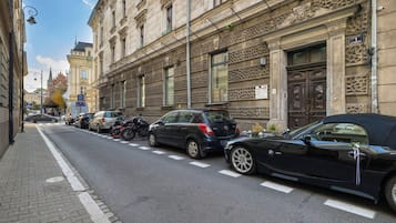 Een straat met geparkeerde auto's en een gebouw met versierde architectuur.