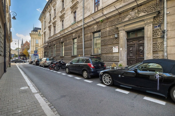 A street with parked cars and a building with ornate architectural details. - Cracow | Celna 1 | Cosy Studio | Air conditioning (Kraków)
