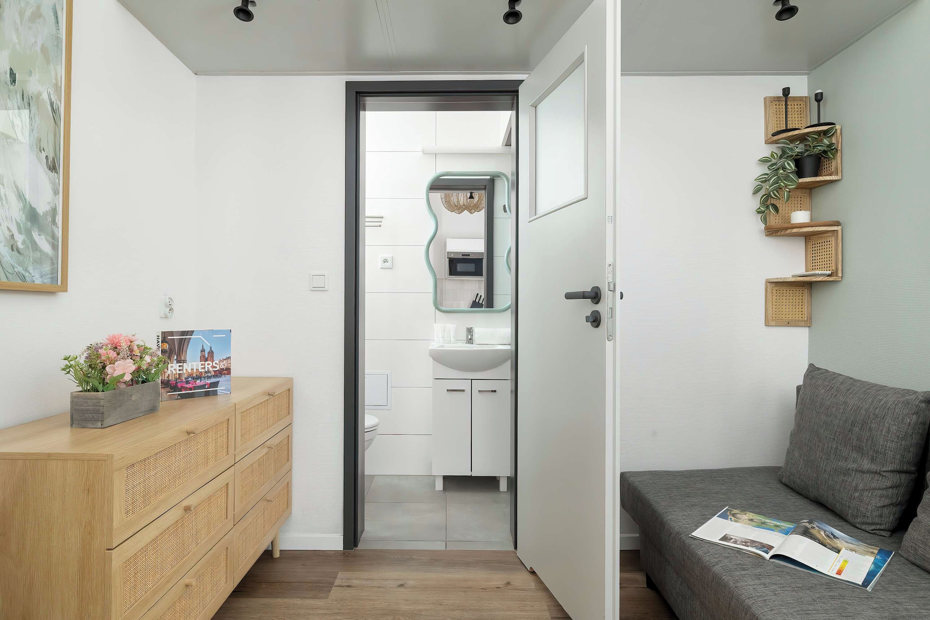 A modern interior with a wooden dresser, a grey sofa, and a wall-mounted plant shelf.