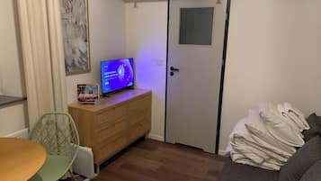 Een kleine kamer met een bed, een kaptafel, een televisie en een deur.