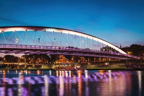 Een brede, verlichte brug over het water, met een stadsgezicht op de achtergrond.