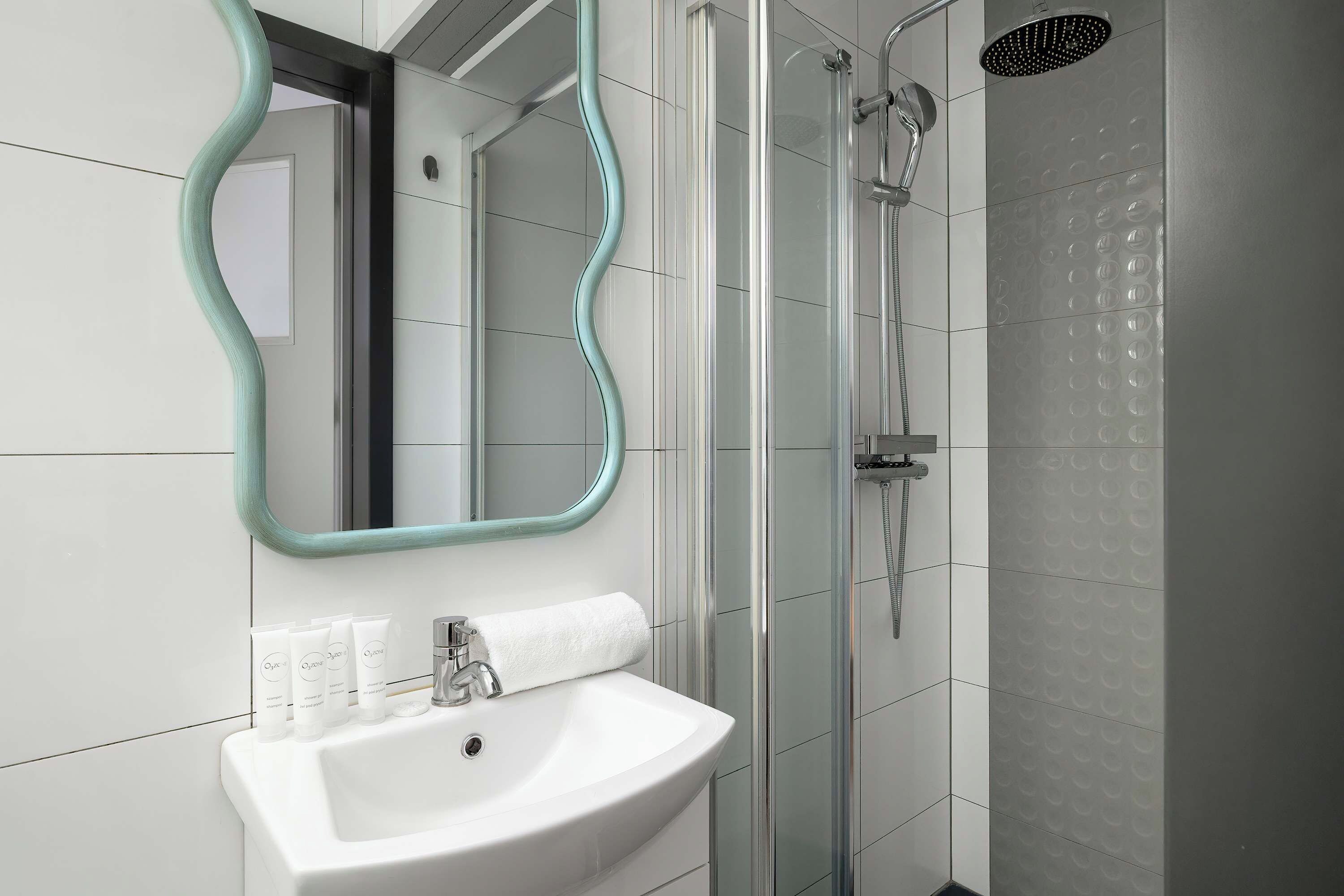 Une salle de bain moderne avec un miroir incurvé, un lavabo blanc et un espace douche.