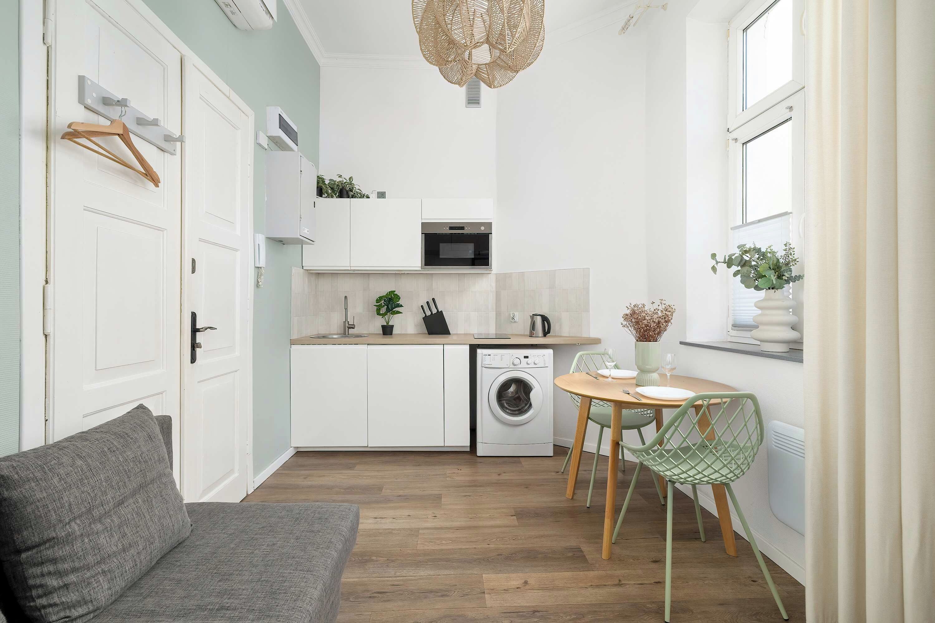 Una cucina funzionale con lavatrice, una zona pranzo con tavolo e sedie, e un divano.