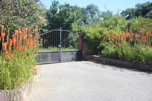 A paved pathway leading to a gated entrance with a metal gate. - Cottage 'L'entredeux' with Shared Terrace, Shared Garden and Wi-Fi (Saint-Viaud)