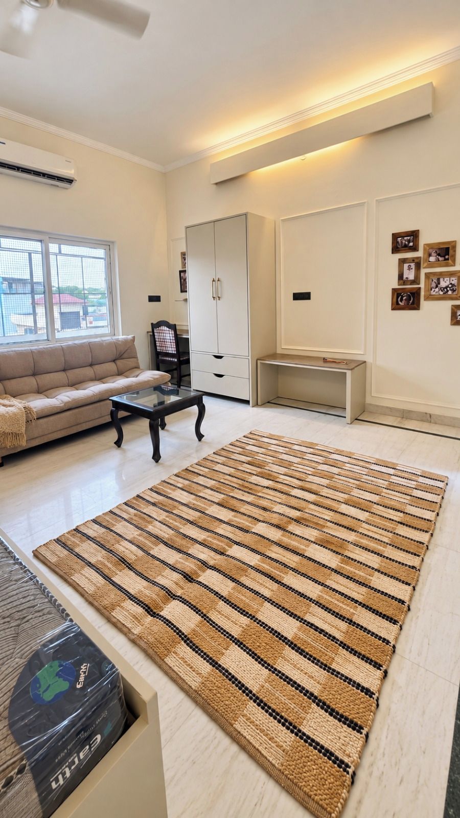 Ein Wohnzimmer mit einem großen Streifen Teppich, einer Couch, einem Couchtisch und einem Schrank.