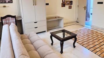 A living room with a sofa, a coffee table, a wardrobe, and a door leading to another room.