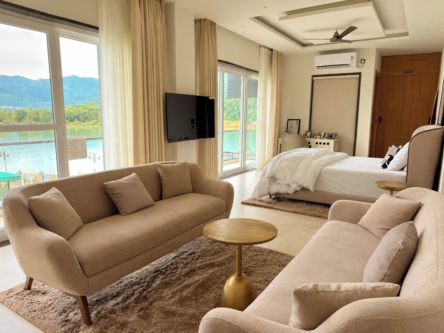 Une chambre d’hôtel avec un canapé, un lit, une télévision et une vue sur un lac.