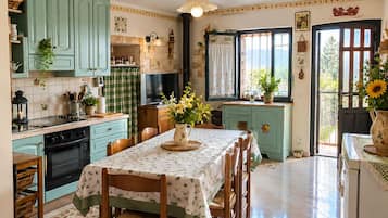 A kitchen with teal cabinets, a dining table with chairs, and a window with a view.