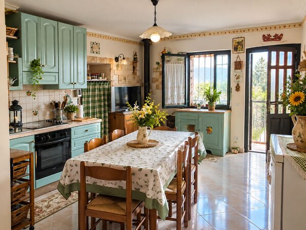 A kitchen with teal cabinets, a dining table with chairs, and a window with a view.