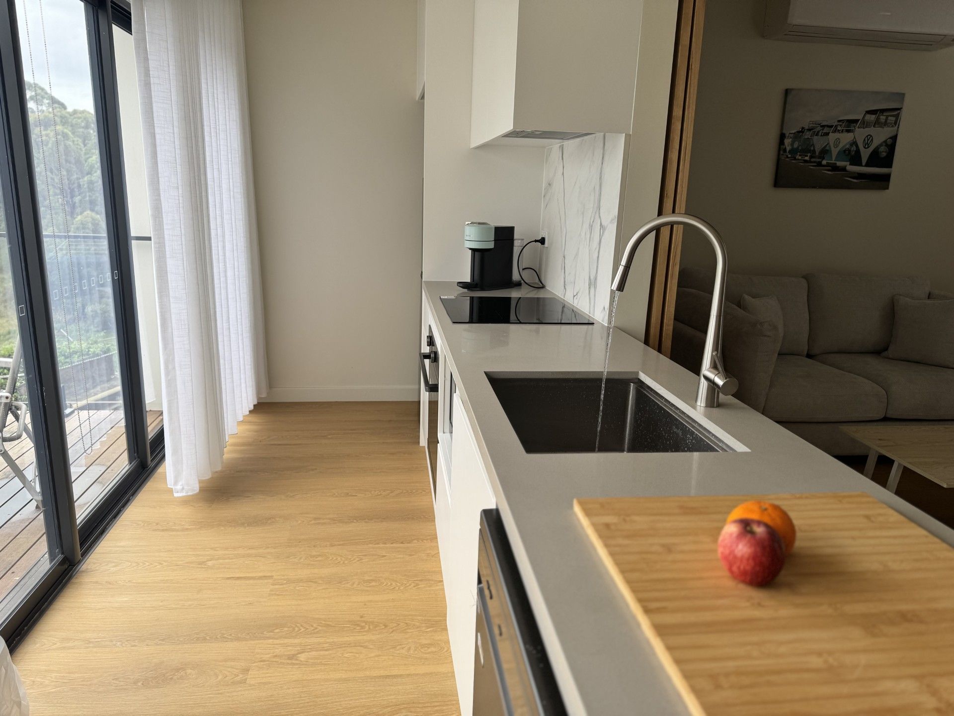 Una cocina moderna con un ventanal grande, un fregadero y una encimera con fruta.