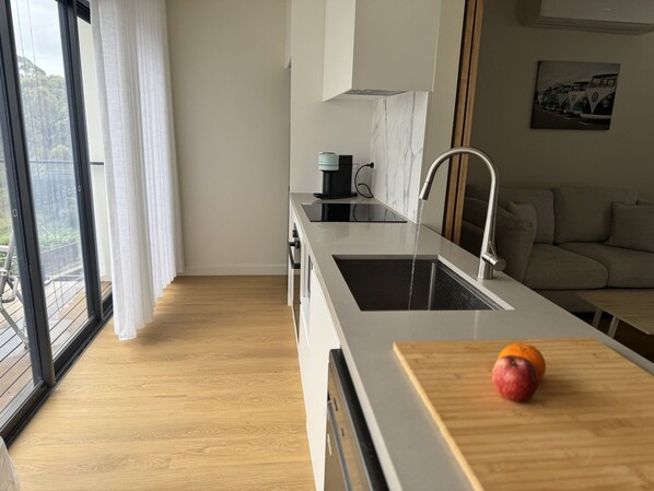 A modern kitchen with a large window, a sink, and a countertop with a fruit.