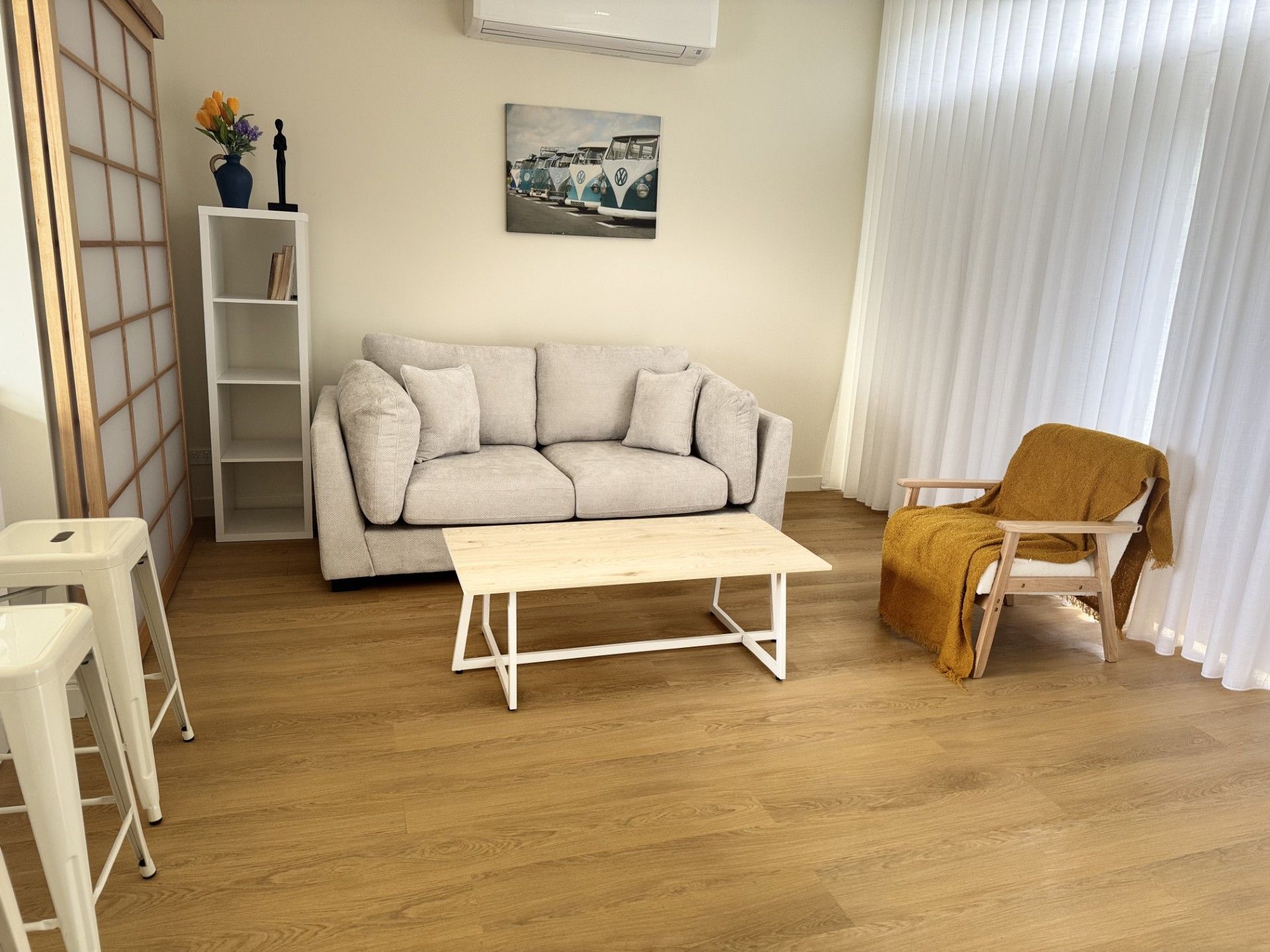 Ein Wohnzimmer mit einer Couch, einem Couchtisch, einem Sessel, einem kleinen Tisch und einem Bücherregal.