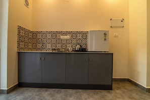 Una kitchenette con salpicadero estampado, un refrigerador blanco y armarios oscuros.
