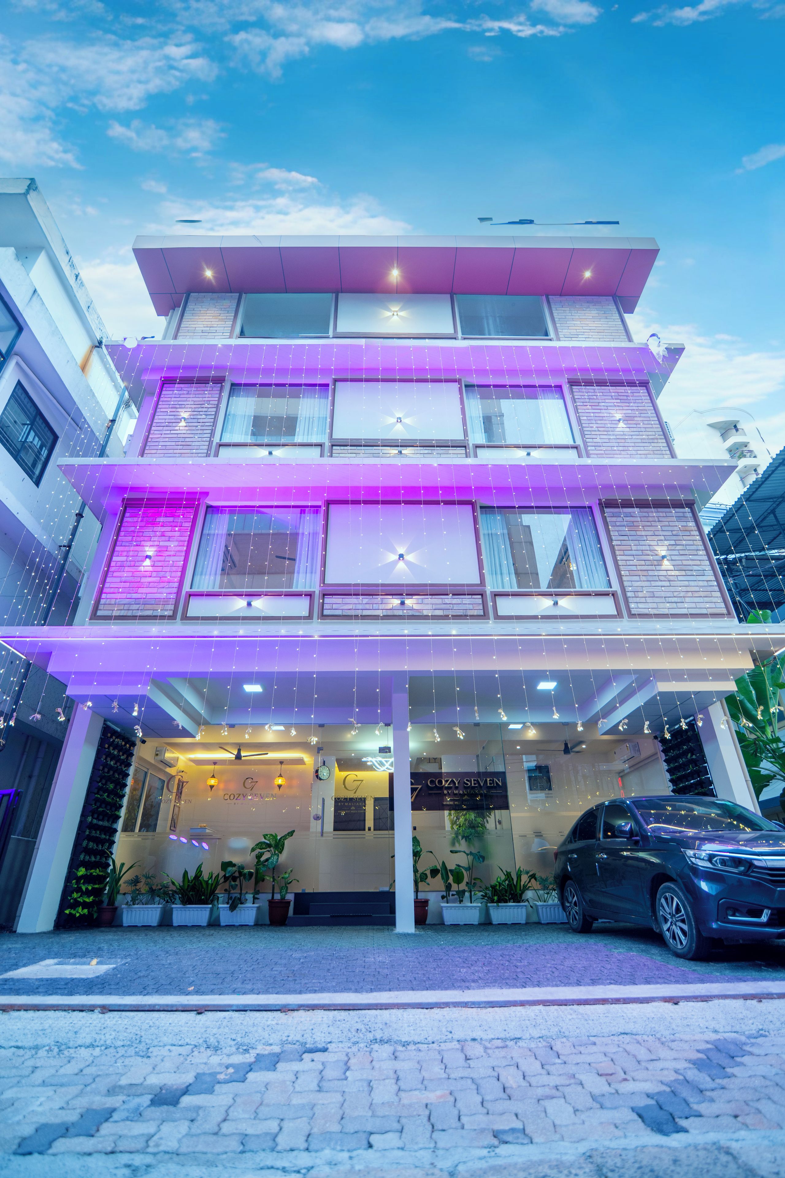 A multi-story building with a modern design, featuring a prominent entrance with a glass facade and outdoor seating area.