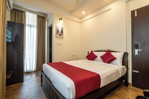Una habitación de hotel con una cama, una puerta, una lámpara y un cartel en la pared.