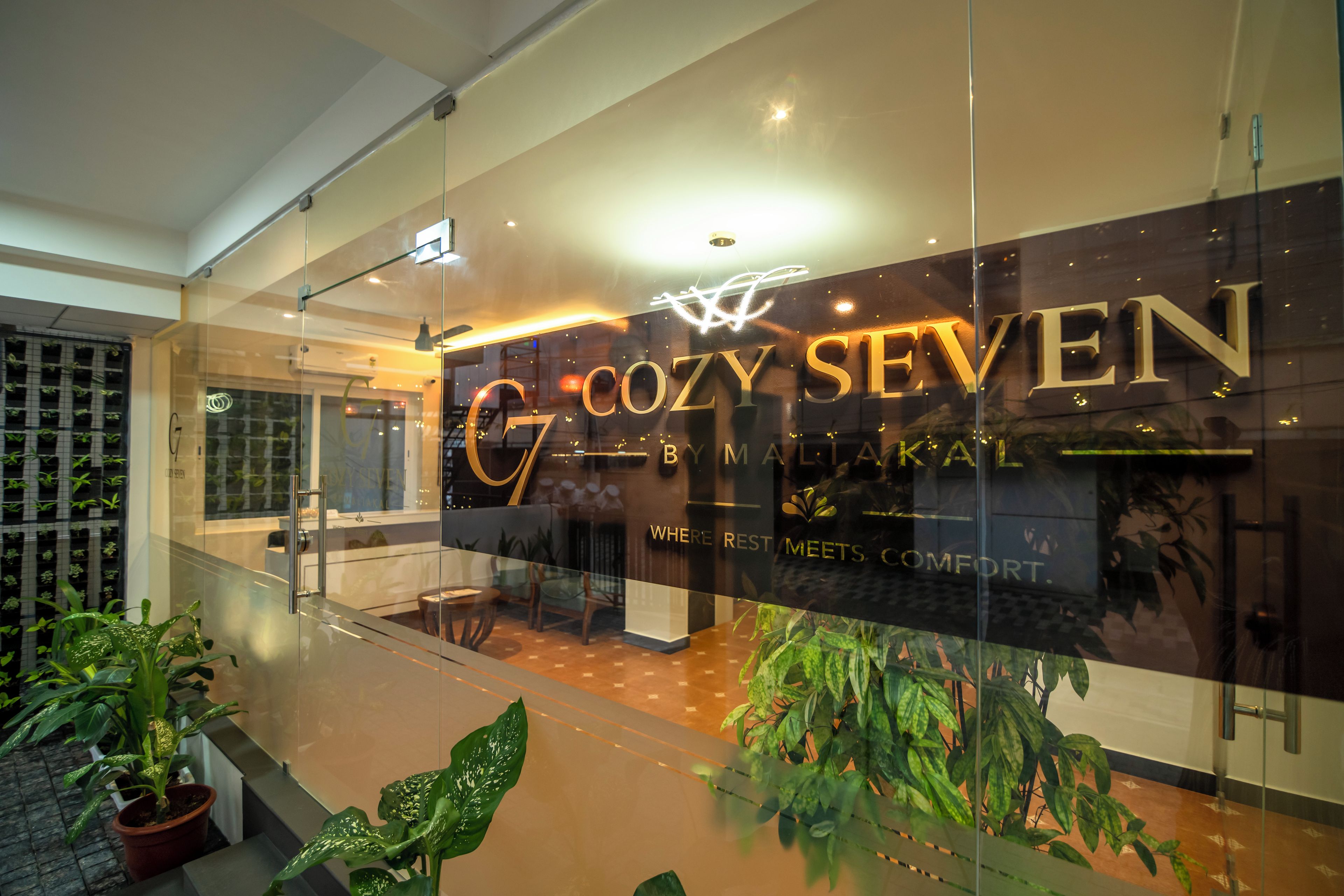 Um interior moderno com uma parede de vidro exibindo o nome 'COZY SEVEN' e uma placa indicando um restaurante.