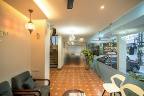 A hotel lobby with a patterned floor, seating area, and a view of the street through a glass wall. - Cozy Seven - 50m to North Railway Station (Kanayannur)