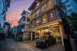 Un edificio moderno con un coche estacionado frente a él, un letrero visible y fachada de ladrillo.