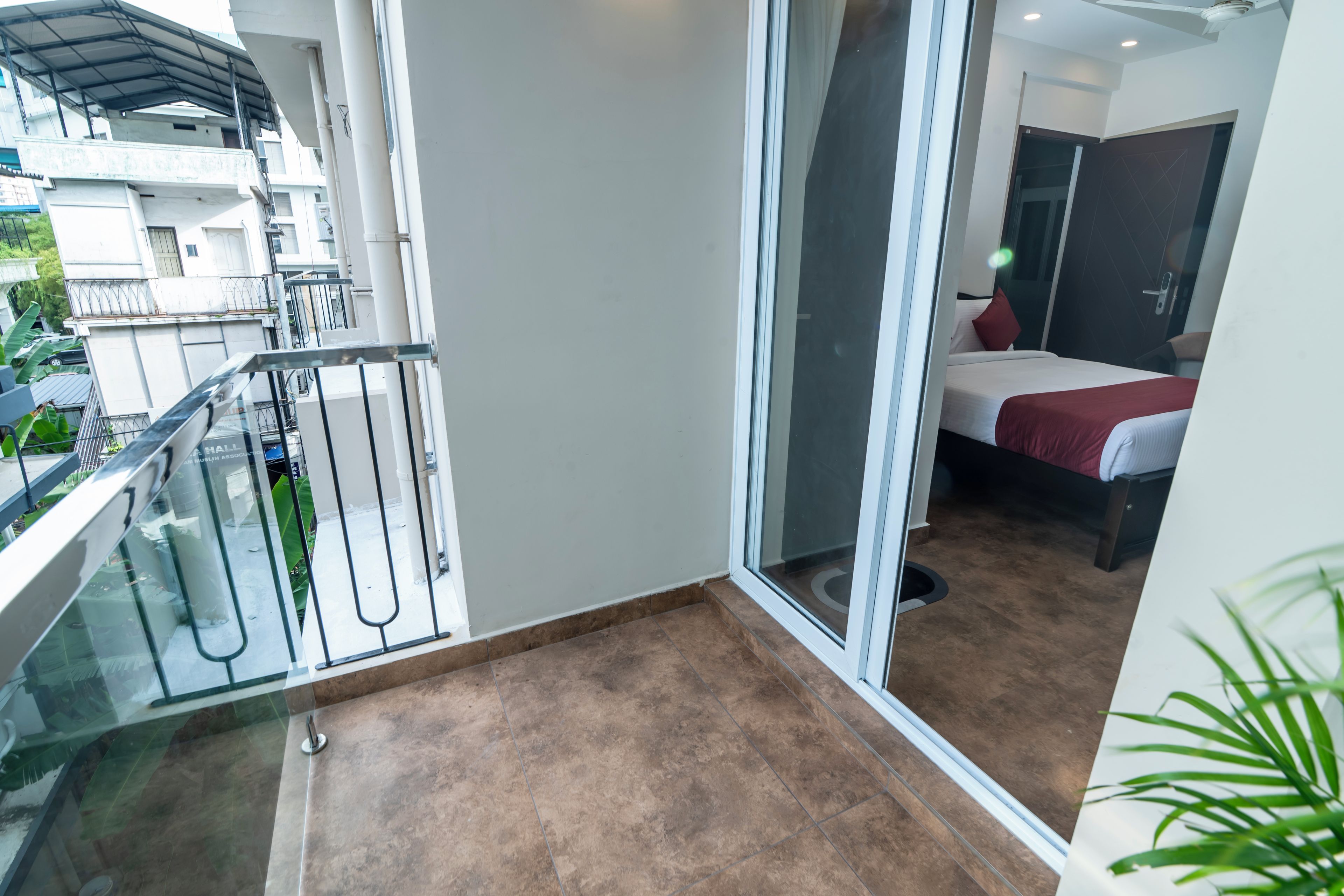 Un balcón con puerta de cristal que da a un dormitorio con cama y almohada roja.