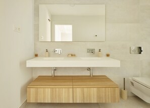 Ein modernes Badezimmer mit einem Doppelwaschtisch, einem großen Spiegel und einem Holzschrank.