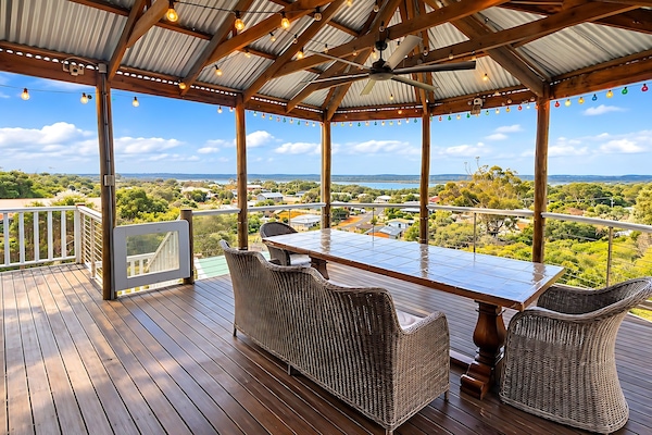 Covered Deck and Outdoor Kitchen : The covered deck at Lake Views & Coastal Escape has a long timber dining table, wicker seating, a ceiling fan and festoon lights, with 180-degree views over Preston Beach to Lake Preston and Yalgorup National Park.