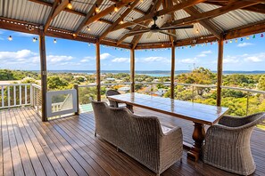 Una terraza techada al aire libre con una mesa y sillas, con vistas a un paisaje pintoresco.