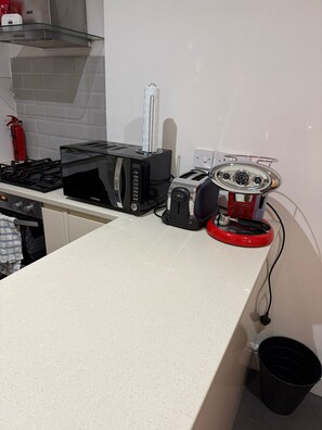 Eine Küche mit einem Gasherd, einer Mikrowelle, einem Toaster und einer roten Kaffeemaschine auf der Arbeitsfläche.
