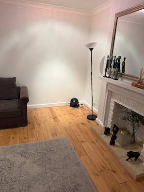 Ein Wohnzimmer mit einer Couch, einer stehenden Stehlampe, einem Kamin und einer kleinen Statue.