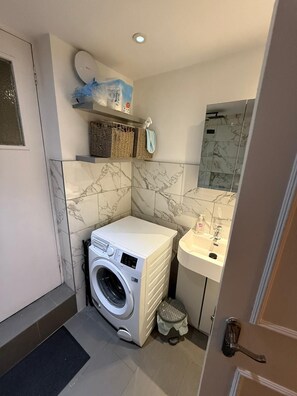 Ein kleiner Hauswirtschaftsraum mit Waschmaschine, Waschbecken und Spiegel.