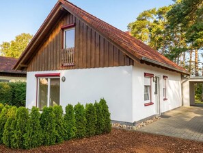 A two-story house with a sloped roof, wooden siding, and a white exterior. - Ferienhaus Fünfseen-Glück (Fünfseen)
