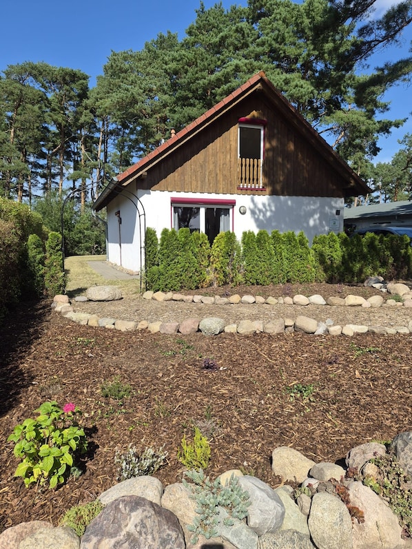 A single-story house with a red roof, white exterior walls, and a small porch with a red awning. - Ferienhaus Fünfseen-Glück (Fünfseen)