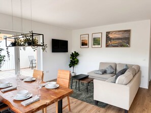 Una sala moderna con comedor, un sofá y un televisor instalado en la pared.