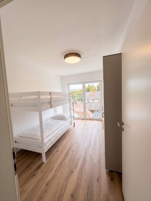 Una habitación con literas, una puerta y vista al exterior por una puerta de vidrio.