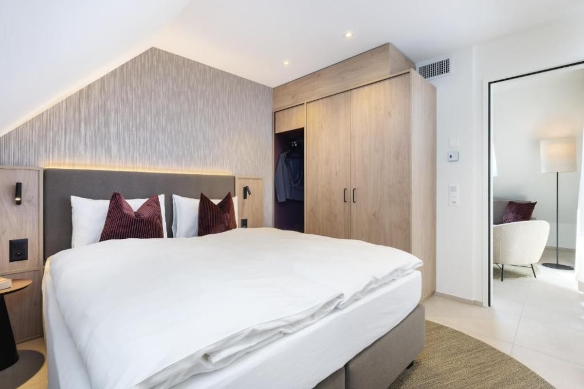 Una habitación de hotel moderna con una cama grande, un armario, un escritorio y una silla.