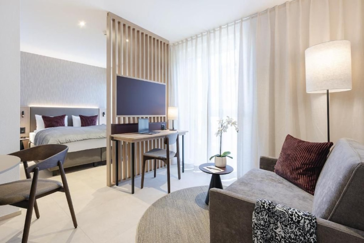 Habitación de hotel moderna con cama, escritorio, sofá y televisor.