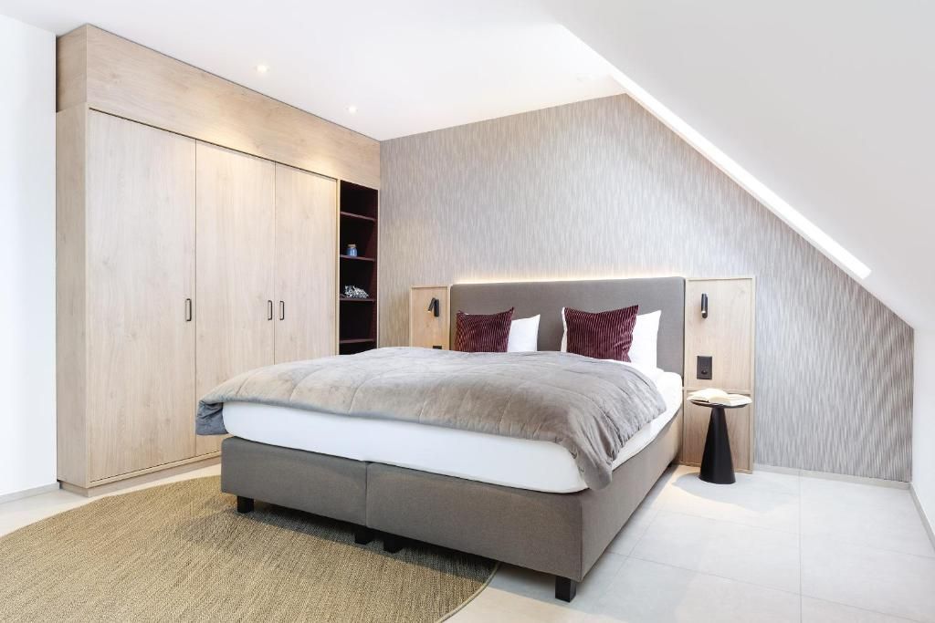 Ein Schlafzimmer mit Bett, Kleiderschrank, Nachttisch und schrägen Wänden.