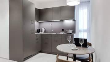 Una cocina moderna con armarios grises, una mesa redonda y una ventana con cortinas de gasa.