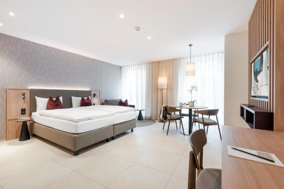 Una habitación de hotel moderna con una cama grande, un escritorio y una silla.