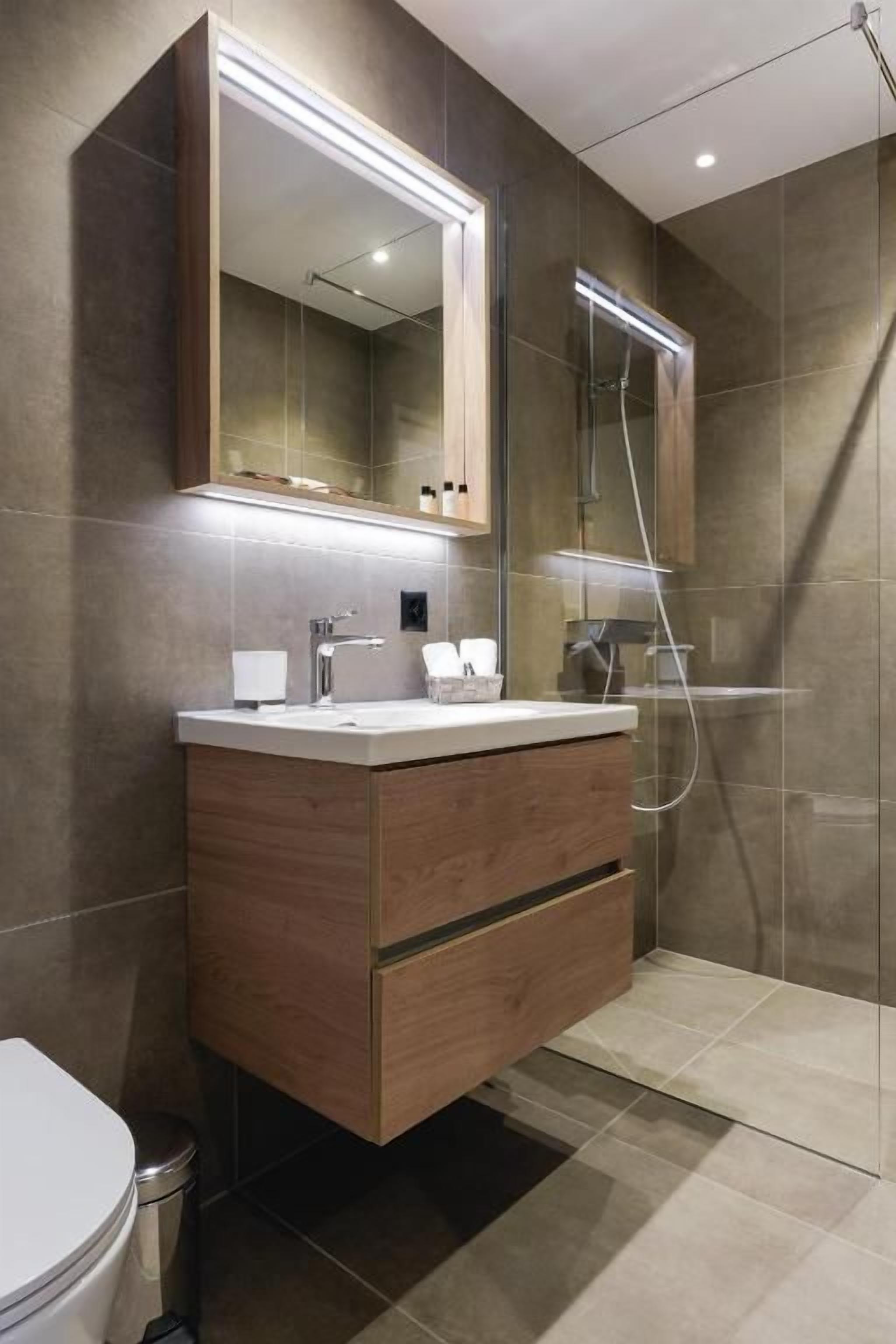 Ein modernes Badezimmer mit Waschtisch, Spiegel und Dusche.
