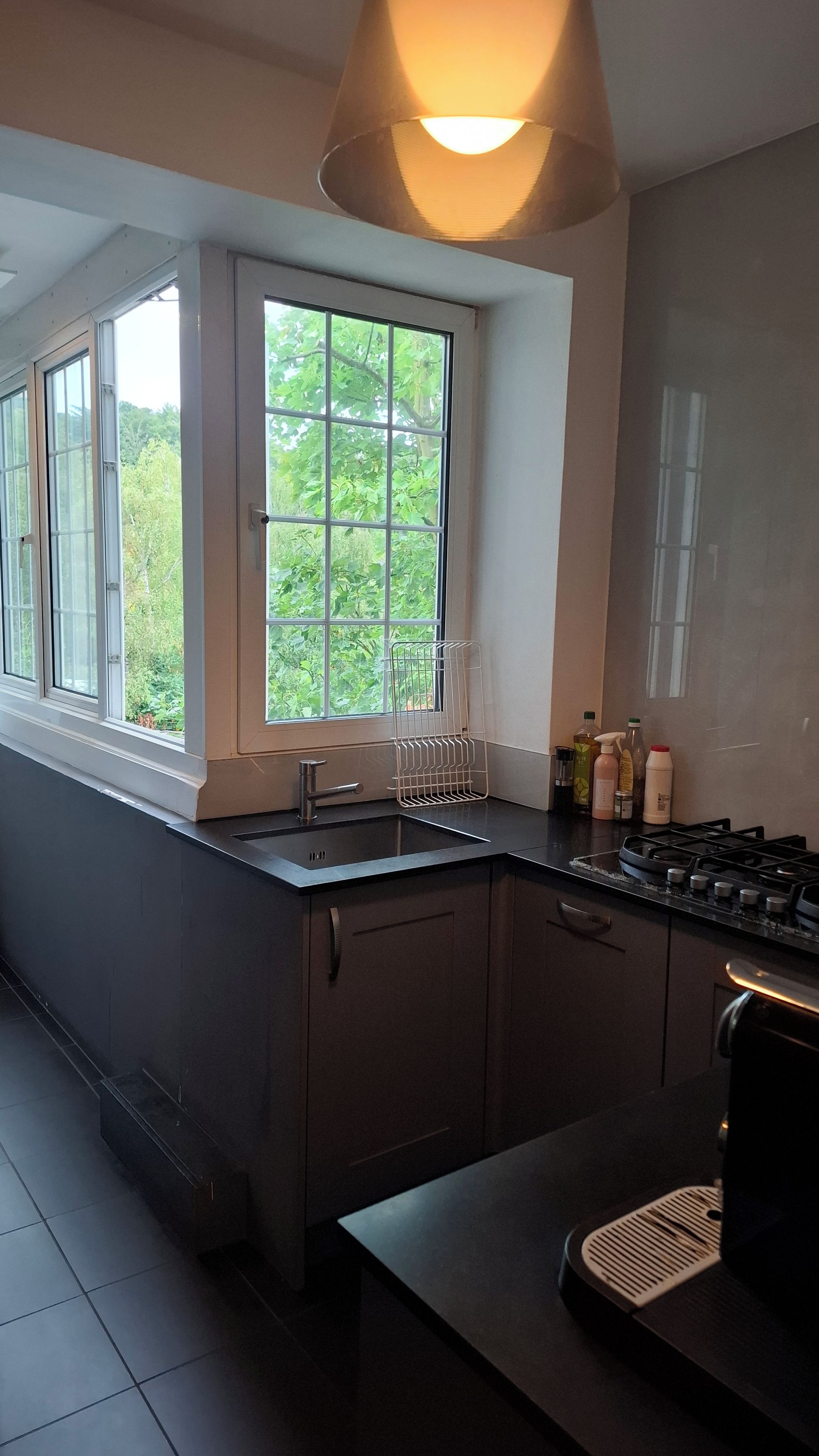 A modern kitchen with a window, a sink, cabinets, and a stove.